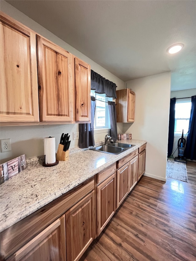 kitchen with dark hardwood / wood-style floors, sink, and light stone counters