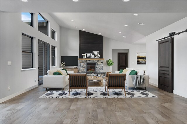 209 Mannington St, Kalispell, MT 59901 - living room with recessed lighting, wood finished floors, a barn door, a stone fireplace, and high vaulted ceiling
