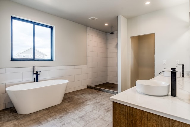209 Mannington St, Kalispell, MT 59901 - bathroom featuring walk in shower, double vanity, a freestanding tub, recessed lighting, and tile walls