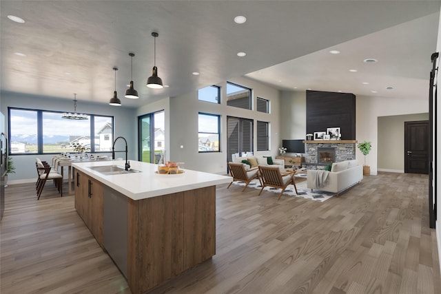 209 Mannington St, Kalispell, MT 59901 - kitchen featuring a stone fireplace, light countertops, a kitchen island with sink, light wood-style floors, and recessed lighting