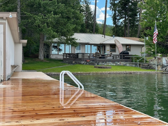 view of dock with a lawn and a water view