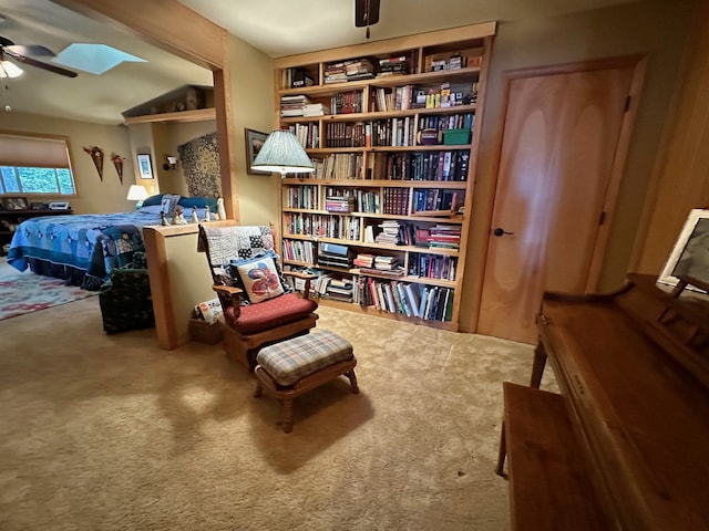 sitting room with carpet flooring, ceiling fan, and a skylight