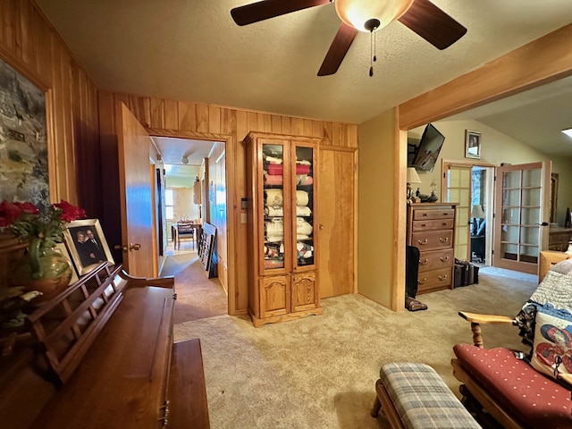 living area featuring wood walls, carpet, and ceiling fan