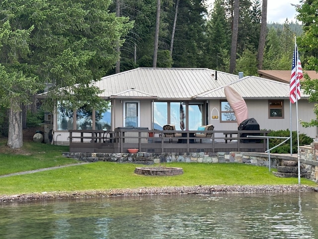 rear view of house featuring a deck with water view and a yard