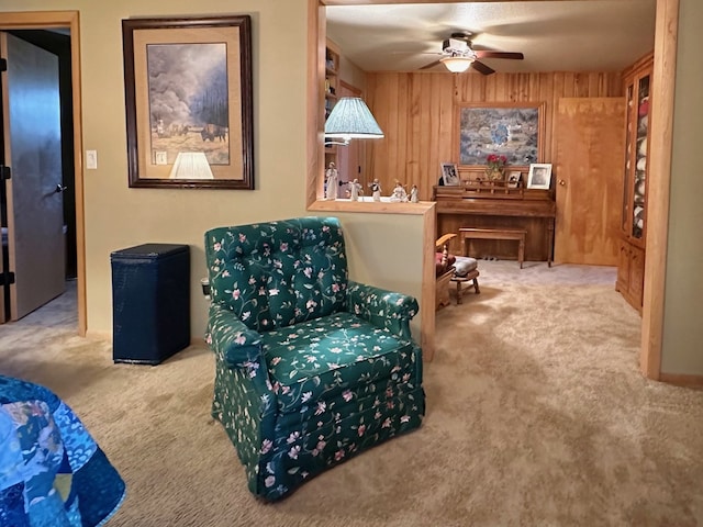 sitting room featuring carpet flooring, ceiling fan, and wooden walls