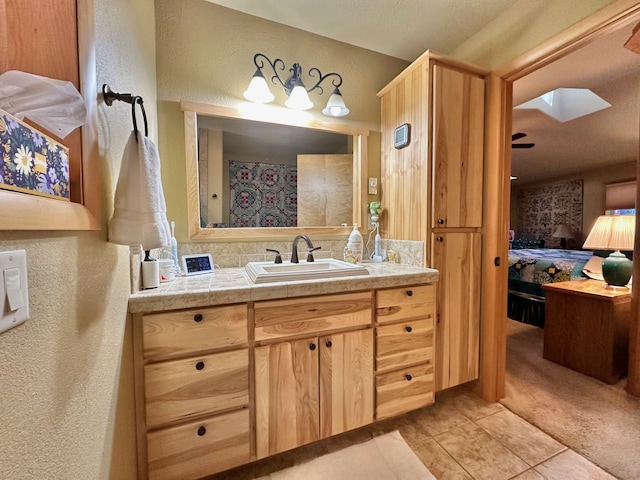 bathroom with tile patterned flooring, vanity, ceiling fan, and a skylight