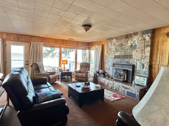 carpeted living room featuring a fireplace and wood walls