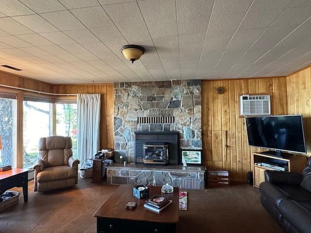 living room with carpet floors, a wall unit AC, a stone fireplace, and wood walls