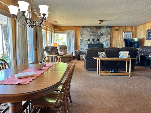 carpeted dining space with a fireplace, a chandelier, a wall unit AC, and wood walls