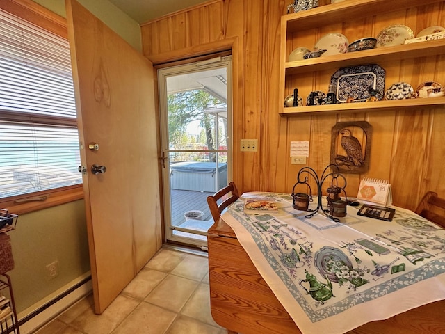 doorway to outside featuring light tile patterned floors, a baseboard heating unit, and wood walls