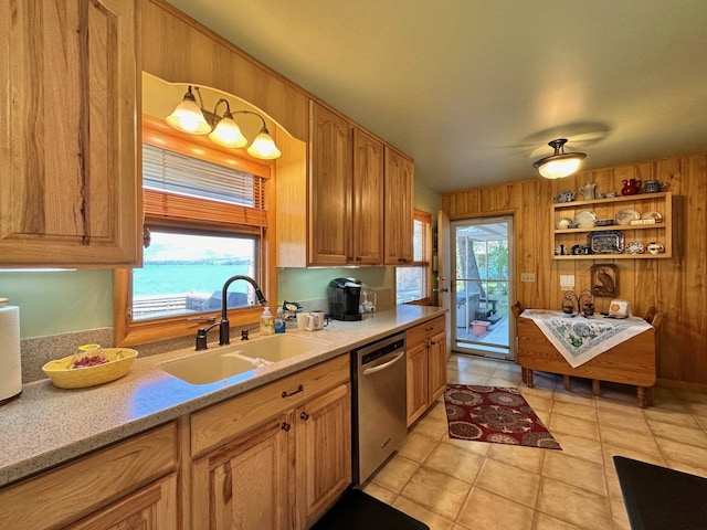 kitchen featuring stainless steel dishwasher, a wealth of natural light, sink, a water view, and wood walls