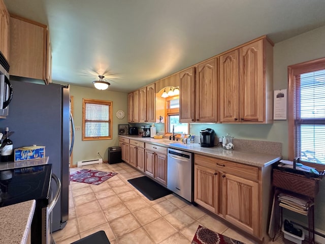 kitchen featuring dishwasher, a baseboard heating unit, plenty of natural light, light tile patterned flooring, and range