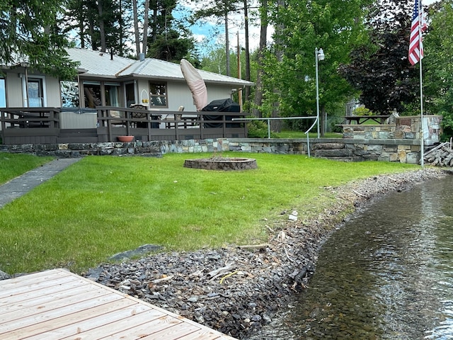 view of yard featuring a fire pit and a deck with water view