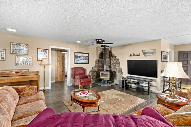 living room with plenty of natural light, ceiling fan, a wood stove, and hardwood / wood-style floors