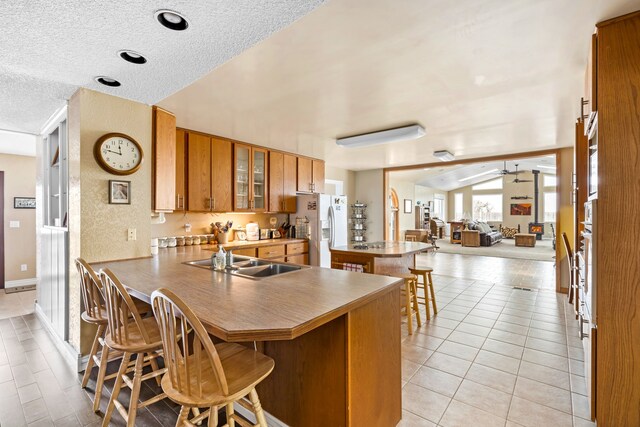 kitchen featuring ceiling fan, light hardwood / wood-style flooring, kitchen peninsula, white appliances, and a kitchen bar