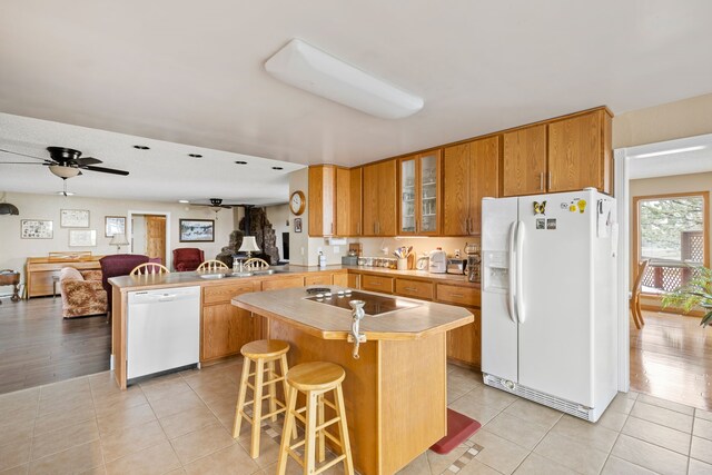 kitchen with built in desk, white appliances, ceiling fan, and light tile floors