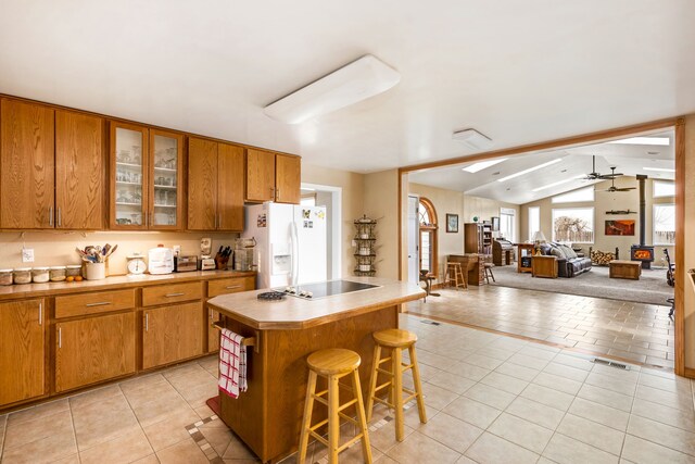 living room featuring ceiling fan, lofted ceiling with skylight, and light tile floors