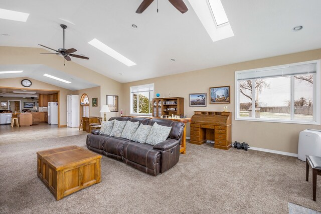 living room with carpet, lofted ceiling with skylight, ceiling fan, and a wood stove