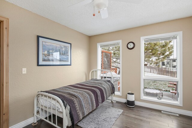 living area featuring a healthy amount of sunlight, hardwood / wood-style floors, ceiling fan, and a textured ceiling