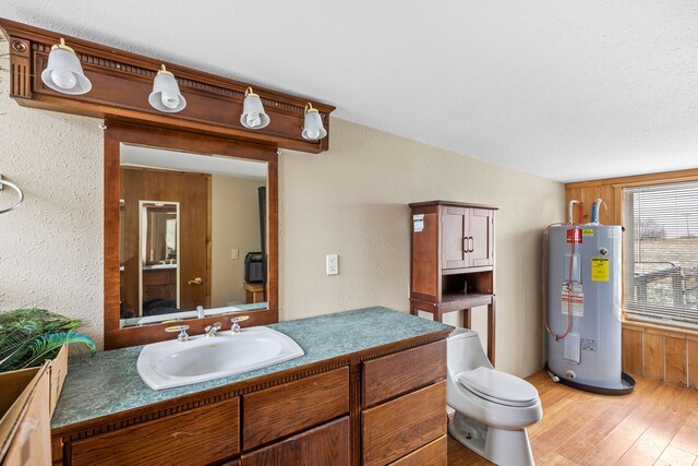 laundry area with sink, a textured ceiling, water heater, and light hardwood / wood-style flooring