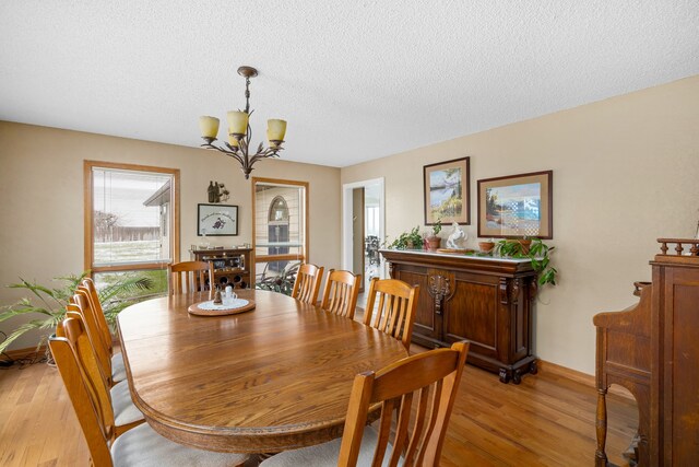 dining space with light hardwood / wood-style flooring, a textured ceiling, and an inviting chandelier