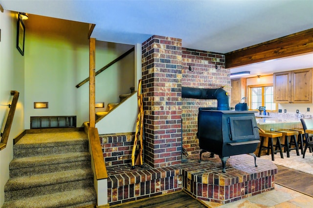 living room featuring hardwood / wood-style flooring, brick wall, and a wood stove