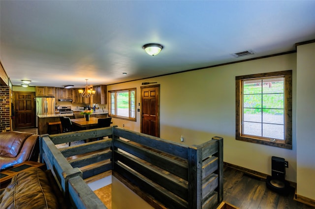 living room featuring a notable chandelier, ornamental molding, hardwood / wood-style flooring, and brick wall