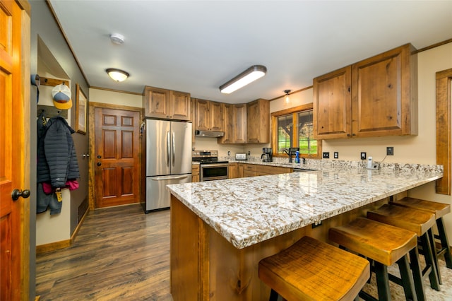 kitchen with a kitchen breakfast bar, ornamental molding, dark hardwood / wood-style flooring, appliances with stainless steel finishes, and kitchen peninsula