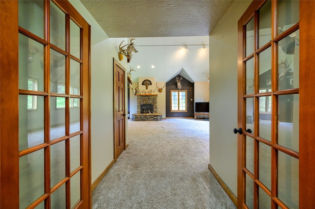 hall with carpet, rail lighting, a textured ceiling, french doors, and lofted ceiling