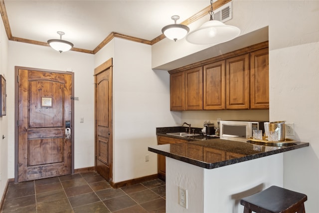 kitchen featuring kitchen peninsula, dark tile flooring, dark stone countertops, a breakfast bar, and pendant lighting