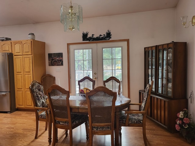 dining room with light hardwood / wood-style floors, french doors, and an inviting chandelier