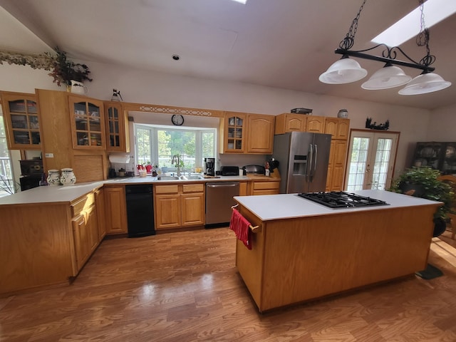 kitchen featuring decorative light fixtures, stainless steel appliances, light wood-type flooring, sink, and a center island