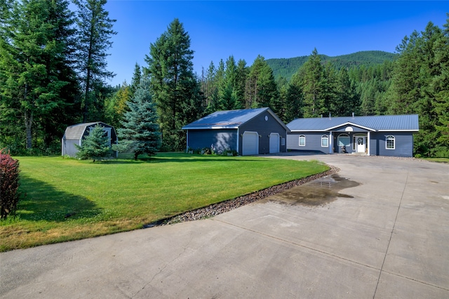 ranch-style house with a garage, an outbuilding, and a front yard