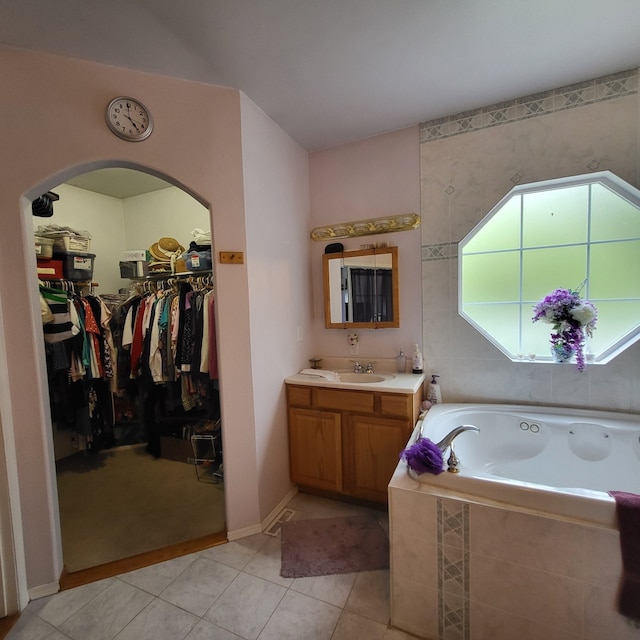 bathroom with tiled bath, tile patterned floors, and vanity