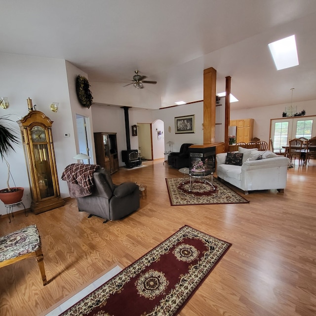 living room with a wood stove, wood-type flooring, ceiling fan, and lofted ceiling