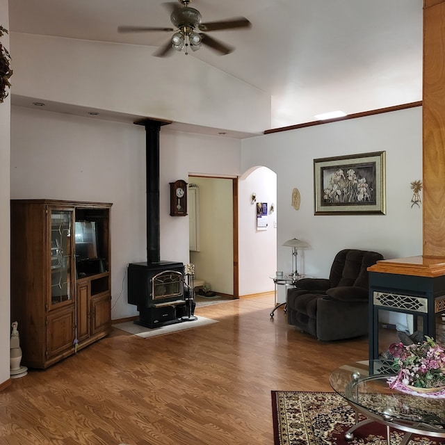 living room featuring vaulted ceiling, ceiling fan, hardwood / wood-style floors, and a wood stove