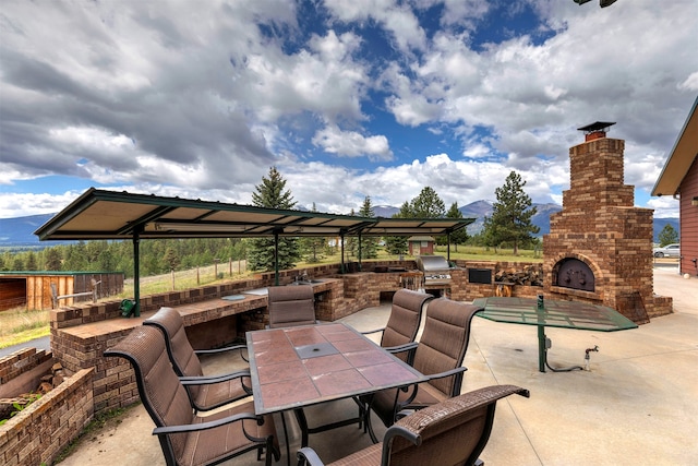 view of patio with area for grilling, exterior kitchen, and exterior fireplace