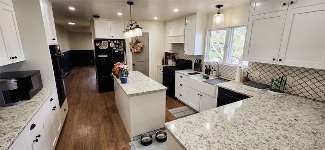 kitchen featuring black appliances, a kitchen island, white cabinetry, and decorative light fixtures