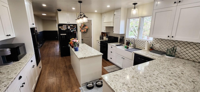 kitchen featuring light stone counters, a kitchen island, black appliances, white cabinets, and dark wood-type flooring