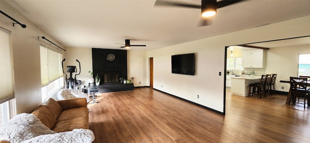 living room featuring ceiling fan, hardwood / wood-style flooring, and a fireplace