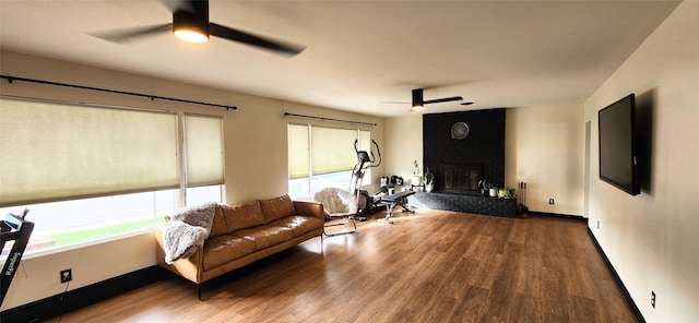 living room featuring hardwood / wood-style floors, ceiling fan, and a large fireplace