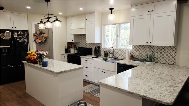 kitchen with black appliances, white cabinetry, custom exhaust hood, and decorative light fixtures