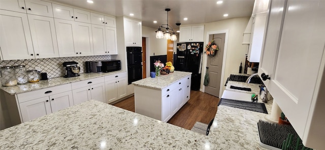 kitchen with a kitchen island, decorative light fixtures, black appliances, white cabinetry, and dark hardwood / wood-style floors