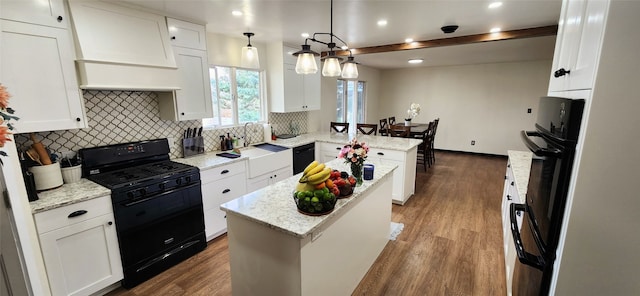 kitchen with white cabinets, pendant lighting, a kitchen island, black appliances, and hardwood / wood-style floors