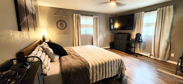 bedroom featuring a baseboard heating unit, hardwood / wood-style floors, and ceiling fan