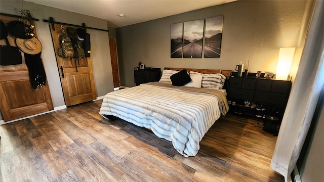 bedroom featuring hardwood / wood-style flooring and a barn door