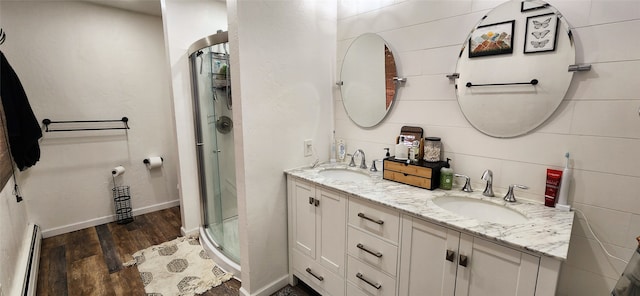 bathroom featuring tile walls, a shower with shower door, vanity, a baseboard radiator, and hardwood / wood-style floors