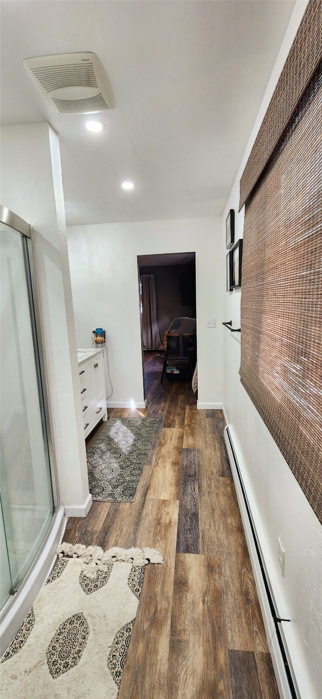 corridor with dark hardwood / wood-style floors and a baseboard heating unit