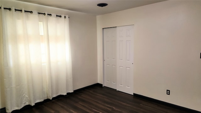 unfurnished bedroom with dark hardwood / wood-style flooring and a closet