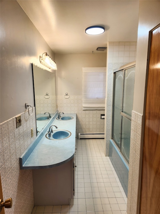 bathroom featuring tile walls, a baseboard radiator, tile patterned floors, bath / shower combo with glass door, and vanity